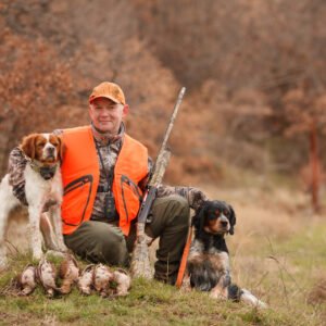 hunter with two hunting dogs, a gun and a woodcock after a hunt